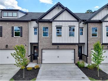 New construction townhome with brick and siding, featuring a two-car garage and manicured landscaping at 5704 Urban Village Way # 3, Tucker, GA 30084