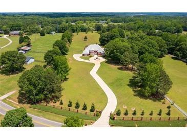 Expansive estate with a brick home, winding driveway, and lush green lawn in a serene, wooded setting at 3030 Berry Rd, Loganville, GA 30052