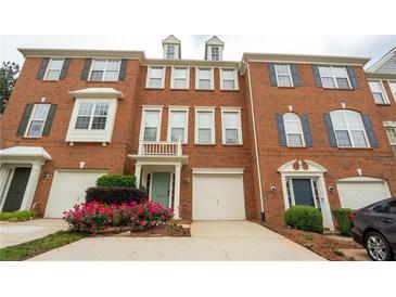 A brick townhouse featuring a one-car garage, trimmed windows, and well-maintained landscaping at 5587 Trace Views Dr, Norcross, GA 30071