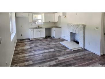 Bright living room featuring a fireplace, updated kitchen cabinets, and modern gray-toned wood laminate flooring at 2040 Chicago Nw Ave, Atlanta, GA 30314