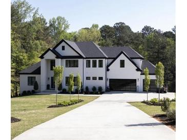 Beautiful modern home showcasing a white exterior, black trim, and spacious driveway at 3681 Hamilton Mill Rd, Buford, GA 30519