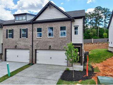 Two-story townhome boasts a brick facade, single-car garage, and well-maintained landscaping at 5710 Urban Village Way # 6, Tucker, GA 30084