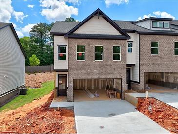 New construction townhome featuring a brick facade, attached two-car garage and modern design elements at 5720 Urban Village Way # 7, Tucker, GA 30084