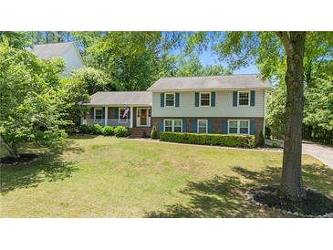 Charming two-story home featuring a lush front lawn, manicured bushes, and brick accents at 4842 Mcpherson Ne Dr, Roswell, GA 30075