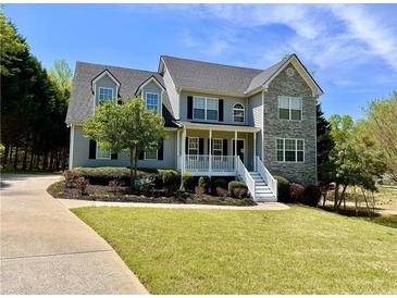 Charming two-story home with stone accents, landscaped lawn, and inviting front porch at 6945 Autumn Hills Dr, Cumming, GA 30028
