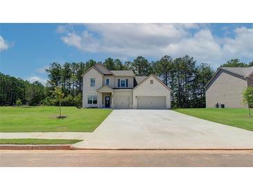 Charming two-story home with a light brick exterior, two-car garage and well-manicured lawn on a sunny day at 211 Linford Dr, Locust Grove, GA 30248