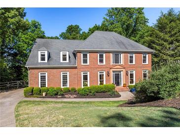 Stately brick home with manicured lawn, mature trees, and tasteful landscaping at 710 Leeds Garden Ter, Alpharetta, GA 30022
