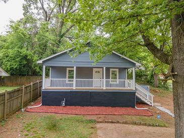 Charming gray house with a cozy front porch and neat landscaping, surrounded by mature trees at 1889 Vesta Ave, Atlanta, GA 30344