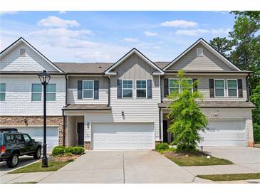Charming townhome featuring a two-car garage, neutral siding, and well-manicured landscaping at 5584 Cannonade Ln, Stonecrest, GA 30058