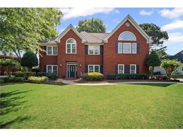 Traditional brick home with a well-maintained lawn and mature landscaping at 6355 Stallion Dr, Cumming, GA 30040