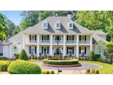 Elegant white home featuring a symmetrical design, stately columns, and mature landscaping at 5045 Harrington Rd, Johns Creek, GA 30022