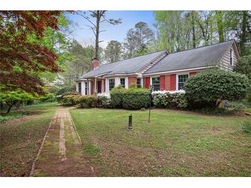 Charming one-story brick home with lush landscaping and a brick pathway to the front door at 491 Hemlock Sw Dr, Marietta, GA 30064