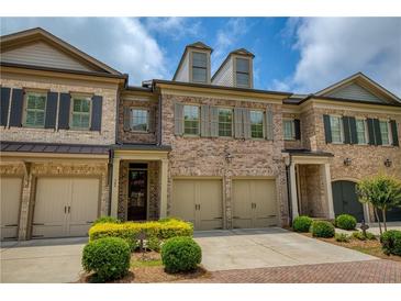 Charming brick townhome with a two-car garage, complemented by manicured landscaping and classic architectural details at 385 Windy Pines Trl, Roswell, GA 30075
