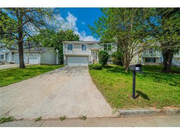 Inviting split-level home featuring a well-manicured lawn and an attached two-car garage at 6082 Raintree Bnd, Lithonia, GA 30058