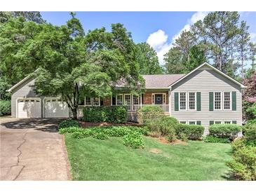 Charming home featuring a manicured lawn, mature trees, and a spacious two-car garage at 4546 Windsor Oaks Ct, Marietta, GA 30066