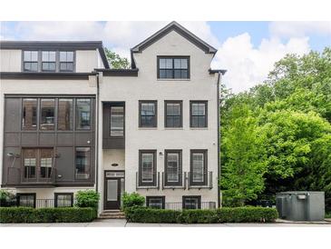 Beautiful three-story townhome featuring a painted brick exterior, dark window trim, and manicured landscaping at 4538 Collins Ave, Sandy Springs, GA 30342