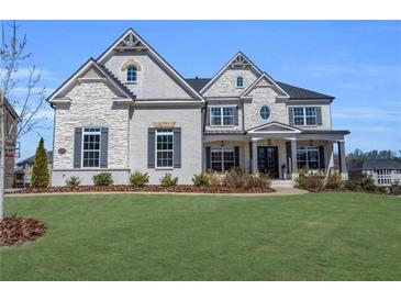 Striking two-story home featuring a combination of painted brick and stone with a well-manicured lawn at 6355 Westfallen Overlook, Cumming, GA 30040