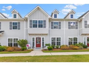 Charming townhome with gray siding, dormer windows, and a welcoming red front door with stylish landscaping at 1700 Prospect Way, Conyers, GA 30094