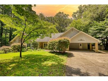 Charming single-story home with a covered entrance, lush lawn, and mature trees in a serene setting at 3601 Club Nw Dr, Kennesaw, GA 30144