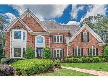 Elegant two-story brick home featuring manicured landscaping and a classic architectural design at 9810 Foxworth Dr, Alpharetta, GA 30022