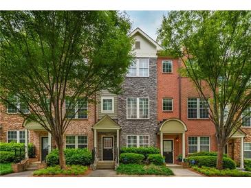 Charming townhouses feature varied brick and stone facades, complemented by lush green trees and manicured landscaping at 1227 Ashford Creek Ne Park, Atlanta, GA 30319