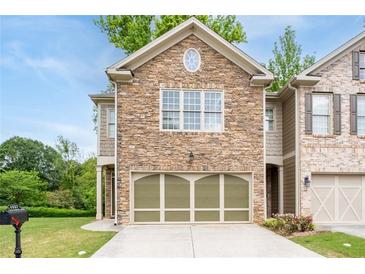 Charming townhome featuring a stone facade, attached two-car garage, and well-maintained landscaping at 4023 Caitlyn Pl, Atlanta, GA 30360
