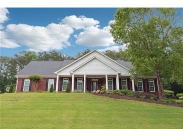 Charming brick home featuring a manicured lawn, black shutters, and a covered front porch at 825 Kennedy Ct, Loganville, GA 30052