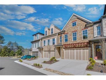 Beautiful multi-level townhomes showcasing stone and brick facades with attached two-car garages at 116 Via Roma, Woodstock, GA 30188