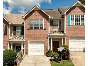 Charming townhome showcasing a brick facade, single-car garage, and neatly landscaped front yard under a bright sky at 5485 Sierra Trl, Atlanta, GA 30349