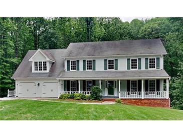Traditional two-story home with a welcoming front porch, attached garage, and mature trees at 2976 Matthew Ln, Lawrenceville, GA 30044
