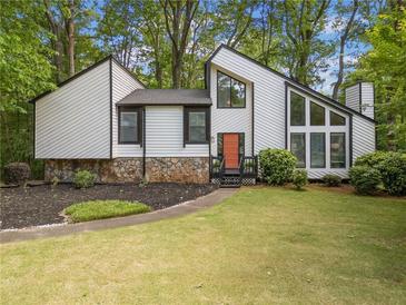 Striking home with modern architecture, multiple windows, a well-manicured lawn, and a stone accent wall at 4514 Creekwood Nw Cir, Kennesaw, GA 30152