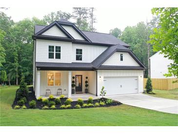 Charming two-story home featuring white siding, black trim, a covered porch, and a well-manicured front yard at 2610 Lisa Sw Dr, Atlanta, GA 30311