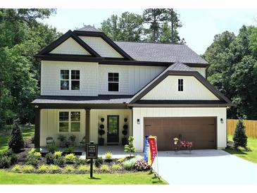 Charming two-story home features a manicured front yard, covered porch, and a two-car garage at 2610 Lisa Sw Dr, Atlanta, GA 30311