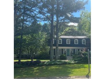 Charming two-story home with a landscaped lawn, blue door and mature trees providing ample shade at 4774 Olde Village Ln, Atlanta, GA 30338