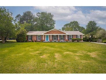 Charming one-story brick home with a spacious front yard and inviting blue door at 599 Honey Creek Rd, Conyers, GA 30094