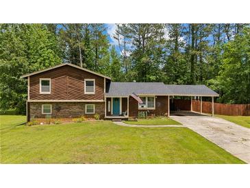 Charming split-level home with a well-manicured lawn, attached carport, and inviting blue front door at 173 Avalon Way, Riverdale, GA 30274