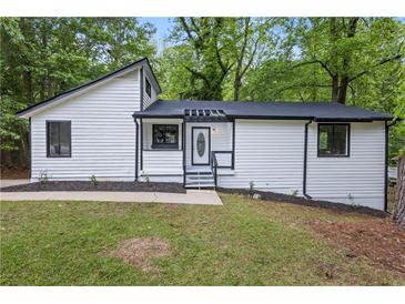 Charming renovated home featuring black trim, white siding, and a well-manicured front lawn at 9438 Cedar Creek Pl, Douglasville, GA 30135