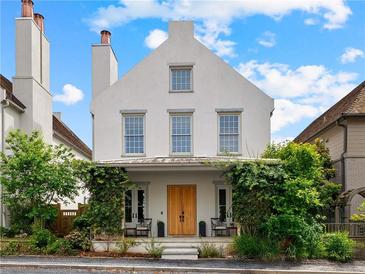 Charming three-story home with a symmetrical facade, covered porch with lush greenery, and striking architectural details at 110 3Rd St, Fayetteville, GA 30214