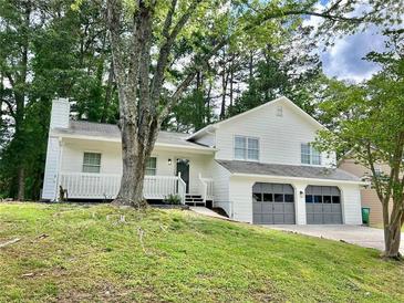 Inviting two-story home with a two-car garage, white siding, a covered porch, and mature trees at 3045 Revere Cir, Snellville, GA 30039