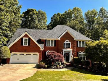 Beautiful two-story red brick home with manicured lawn, lush landscaping, and a two-car garage at 420 Windswept Ct, Roswell, GA 30075