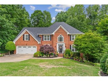 Charming two-story brick home with a well-manicured lawn, lush landscaping, and a two-car garage at 420 Windswept Ct, Roswell, GA 30075