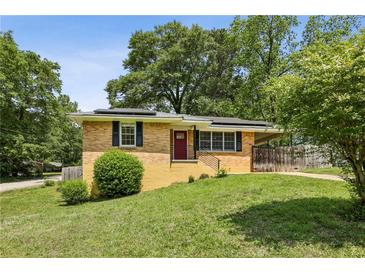 Charming brick home with solar panels, a well-manicured lawn and a bright red front door at 3314 Glenco Dr, Decatur, GA 30032