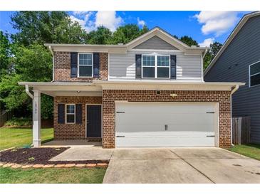 Charming two-story home featuring a brick facade, gray siding, and a two-car garage at 10786 Wheeler Trce, Hampton, GA 30228