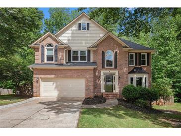 Charming two-story brick home featuring an attached two-car garage and a well-maintained front lawn at 300 Wesfork Nw Way, Suwanee, GA 30024