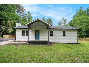 Charming one-story home featuring white siding, a cozy porch, and a beautifully landscaped front yard surrounded by mature trees at 3952 Leisure Se Ct, Conyers, GA 30013