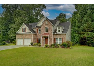 Charming two-story brick home with manicured lawn, lush landscaping, and a welcoming double door garage at 4942 Brown Leaf Dr, Powder Springs, GA 30127