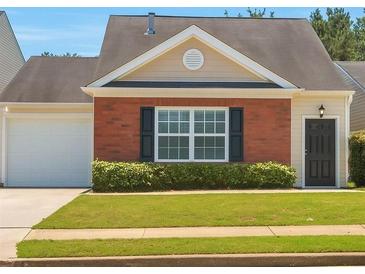 Charming single-story home featuring brick accents, a well-manicured lawn, and an attached garage at 1015 Lakeside Cir, Covington, GA 30016