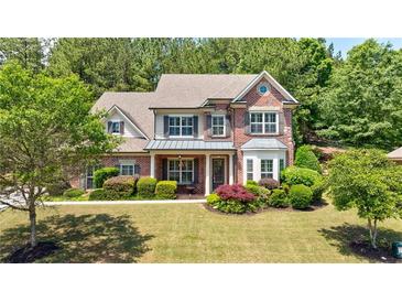 Charming two-story brick home with manicured lawn, lush landscaping, and inviting front porch at 621 Oakbourne Way, Woodstock, GA 30188