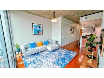 Bright living room with a modern sofa, blue accent rug, and neutral walls at 860 Peachtree Ne St # 1411, Atlanta, GA 30308