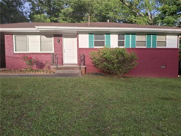Charming brick home features a well-manicured lawn, white trim, and teal shutters at 947 Meadow Rock Dr, Stone Mountain, GA 30083